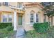 Inviting townhome entrance with verdant landscaping, an arched entrance, and a green front door at 2605 Andros Ln, Kissimmee, FL 34747