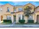 Charming townhome featuring a red tile roof, manicured landscaping, and a welcoming green front door at 2605 Andros Ln, Kissimmee, FL 34747