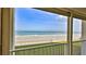 Balcony view of a beach with blue skies and ocean, and a railing at 4175 S Atlantic Ave # 232, New Smyrna Beach, FL 32169