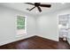 Cozy bedroom with dark wood floors, white walls, a ceiling fan, and natural light from a window at 632 Tildenville School Rd, Winter Garden, FL 34787