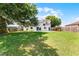 A spacious backyard with lush green grass, solar panels, and mature trees at 119 Floral Ct, Kissimmee, FL 34743
