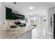 Bright kitchen features stainless steel appliances, green cabinets, marble countertop, and white tile flooring at 119 Floral Ct, Kissimmee, FL 34743