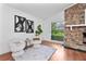 Bright sitting area by a stone fireplace, featuring stylish chairs, modern artwork, and lots of natural light at 1221 Thunder Trl, Maitland, FL 32751