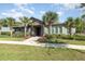 Community clubhouse entrance featuring mature palm trees, lush flower beds, and a well-maintained lawn at 13557 Parkfield Way, Winter Garden, FL 34787
