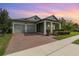 Charming home with a two-car garage, brick driveway, and inviting front porch with colorful landscaping at 13557 Parkfield Way, Winter Garden, FL 34787