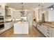 Spacious kitchen boasts white cabinetry, stainless appliances, large island, and wood-look tile flooring at 15138 Shonan Gold Dr, Winter Garden, FL 34787