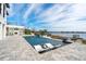 Stunning pool area with waterfront views, featuring sleek lounge chairs and an outdoor fireplace for ultimate relaxation at 15138 Shonan Gold Dr, Winter Garden, FL 34787