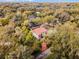 Aerial view of a charming home with a red tile roof, surrounded by mature trees and lush greenery at 2004 Magnolia Ave, Sanford, FL 32771