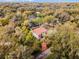 Aerial view of a charming home with a red tile roof, surrounded by mature trees and lush greenery at 2004 Magnolia Ave, Sanford, FL 32771