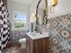 Stylish bathroom featuring patterned tile, a wood vanity, and a decorative mirror with sconces at 2004 Magnolia Ave, Sanford, FL 32771