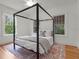 Minimalist bedroom featuring a four-poster bed, wood floors, and ample natural light from the windows at 2004 Magnolia Ave, Sanford, FL 32771