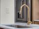 Close up of a kitchen sink with a brass faucet and white countertop, with stainless steel appliance in the background at 2004 Magnolia Ave, Sanford, FL 32771