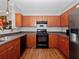 Well-lit kitchen features sleek black appliances and ample wood cabinets with dark countertops and wood flooring at 204 E South St # 2052, Orlando, FL 32801