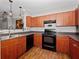 Efficient kitchen with wood cabinetry, black appliances, and laminate countertops at 204 E South St # 2052, Orlando, FL 32801