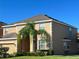 Two-story house with tan exterior, landscaping, and a two-car garage at 2553 Dharma Cir, Kissimmee, FL 34746
