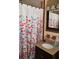 Bathroom features tiled floors, floral shower curtain, and modern sink at 423 Longfellow Blvd, Lakeland, FL 33801