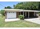 View of the home with an attached garage, a covered carport and a well manicured front lawn at 423 Longfellow Blvd, Lakeland, FL 33801