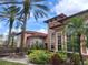 Elegant Mediterranean-style home featuring a red tile roof, arched windows, and lush tropical landscaping at 5518 Metrowest Blvd # 104, Orlando, FL 32811