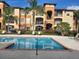 Community pool and building featuring lounge chairs and tropical landscaping on a sunny day at 5518 Metrowest Blvd # 10, Orlando, FL 32811