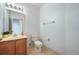 Half bathroom featuring a toilet, vanity, mirror, and neutral tile at 7189 Regina Way, Orlando, FL 32819