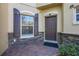 Close-up of a front entrance showing stone detailing, brick pathway, and a dark brown front door at 7189 Regina Way, Orlando, FL 32819