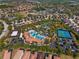 Aerial view of a resort-style community pool area with lush landscaping, tennis courts, and ample parking at 7343 Oakmoss Loop, Davenport, FL 33837