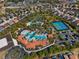 Aerial shot of a vibrant community pool complex with multiple pools, water features, tennis courts, and shaded lounging areas at 7343 Oakmoss Loop, Davenport, FL 33837