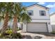 Two-story home featuring a two-car garage, brick-paved driveway and lush palm trees at 7343 Oakmoss Loop, Davenport, FL 33837