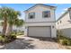 Two-story home featuring a two-car garage, brick-paved driveway and blue accents around the windows at 7343 Oakmoss Loop, Davenport, FL 33837