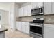 Kitchen with stainless steel appliances, white cabinetry, and granite countertops at 7343 Oakmoss Loop, Davenport, FL 33837