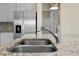 Close-up of a stainless steel kitchen sink with a granite countertop and stainless steel refrigerator at 7343 Oakmoss Loop, Davenport, FL 33837