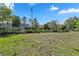 Vacant lot with green grass, surrounded by trees and houses in the background at 7343 Oakmoss Loop, Davenport, FL 33837