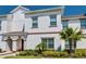 A bright white two-story townhome with a landscaped front yard at 9023 Dogleg Dr, Davenport, FL 33896