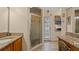 Well-lit bathroom with a glass-door shower, vanity, granite countertop and a small window at 9664 Lake Douglas Pl, Orlando, FL 32817