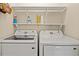 Modern laundry room featuring a side-by-side washer and dryer with upper shelving at 9664 Lake Douglas Pl, Orlando, FL 32817