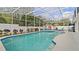 Screened-in pool area with a large pool and spa, surrounded by lush landscaping at 9664 Lake Douglas Pl, Orlando, FL 32817