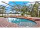 Screen enclosed in-ground pool surrounded by brick pavers and manicured landscaping at 1000 Parasol Pl, Oviedo, FL 32766