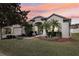 Beautiful home exterior with a manicured lawn, palm trees, and a colorful sunset backdrop at 369 Belhaven Falls Dr, Ocoee, FL 34761