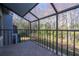 Enclosed balcony with tile floors and views of a wooded area through the black metal railing at 4765 Capri Pl # 209, Orlando, FL 32811