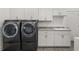 Efficient laundry room with modern washer and dryer, ample storage cabinets, and a utility sink at 530 Sanctuary Blvd, Winter Haven, FL 33881