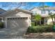 Tan two-story townhome with two-car garage and mature palm trees at 980 Crestwood Commons Ave, Ocoee, FL 34761