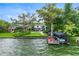 Waterfront view of home with boat dock, lush lawns and tall trees at 1336 College Pt, Winter Park, FL 32789