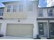 Two-story townhome with light beige siding, a two-car garage, and a well-manicured lawn at 1826 Sanibel Dr, Davenport, FL 33896