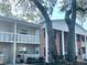 Charming condo building featuring brick accents, balconies, and beautiful mature trees at 2500 Lee Rd # 202, Winter Park, FL 32789