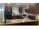 Well-lit kitchen features granite countertops, stainless steel appliances and dark wood cabinetry at 2500 Lee Rd # 202, Winter Park, FL 32789