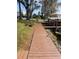 A wide, inviting boardwalk leads through a lush yard, lined with mature trees towards the waterfront at 2500 Lee Rd # 202, Winter Park, FL 32789
