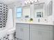 This bathroom has double sinks with gray cabinets, modern mirrors, and tiled shower at 8130 Yellow Crane Dr, Kissimmee, FL 34747
