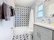 This bathroom has a star pattern, tiled shower with a white curtain, and a sink with a gray cabinet at 8130 Yellow Crane Dr, Kissimmee, FL 34747