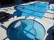 An in-ground pool features a jacuzzi and steps leading to the swimming area at 8130 Yellow Crane Dr, Kissimmee, FL 34747