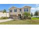 Inviting two-story home with a well-manicured lawn, palm trees, and neutral stucco exterior at 11434 Wishing Well Ln, Clermont, FL 34711